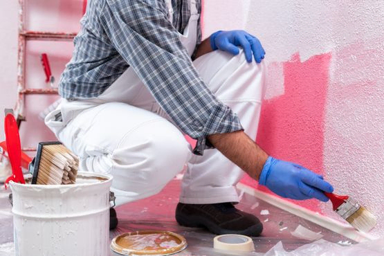 Pintor pintando pared de rosa